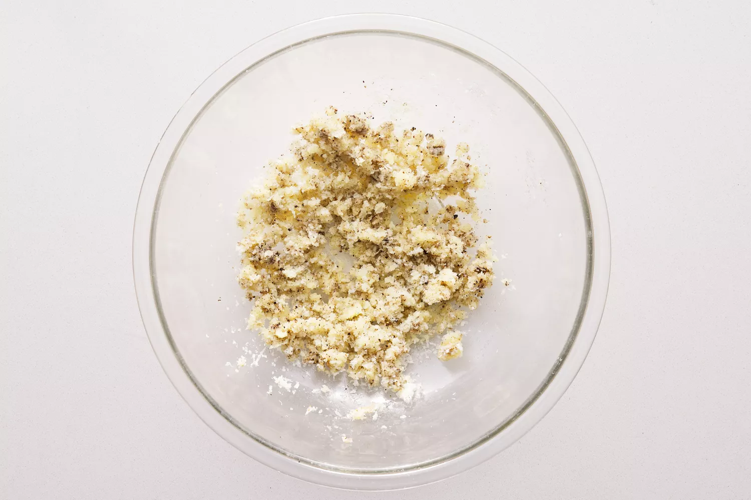 Grated Pecorino with seasonings in a glass bowl.