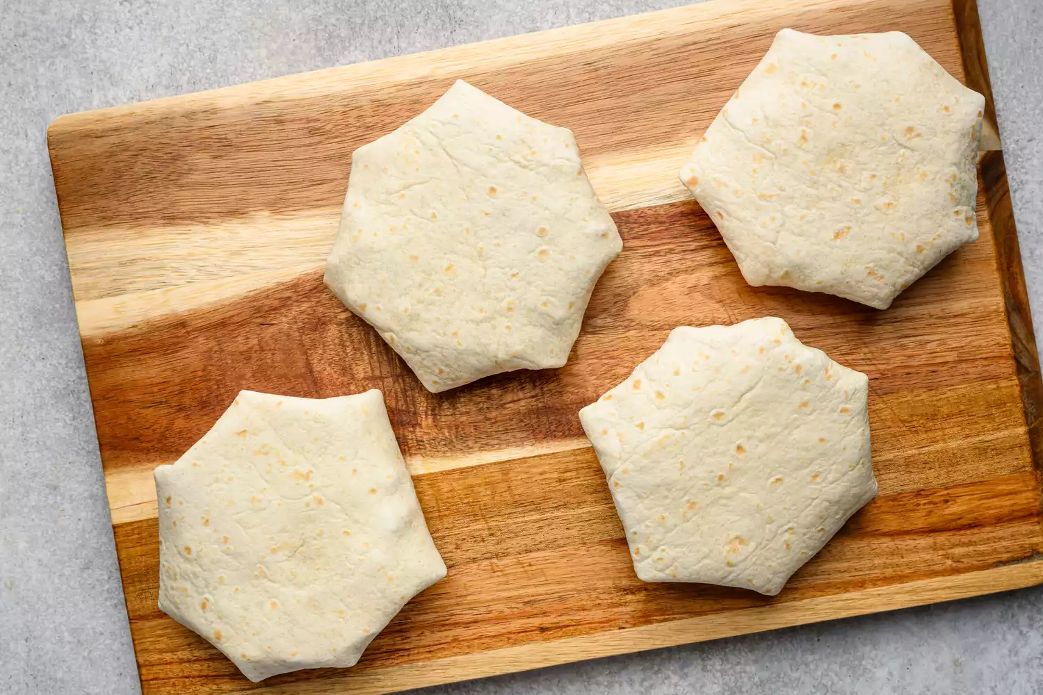 Une planche à découper avec quatre Crunchwraps pliés, côté couture vers le bas