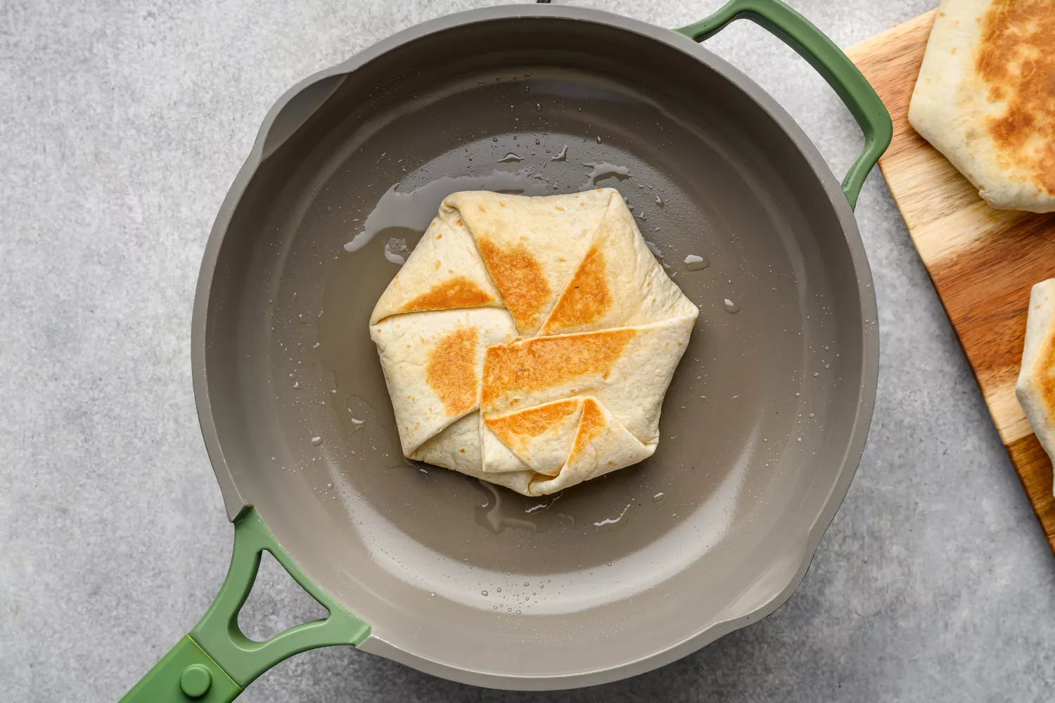 Une poêle antiadhésive huilée avec un Crunchwrap Supreme doré