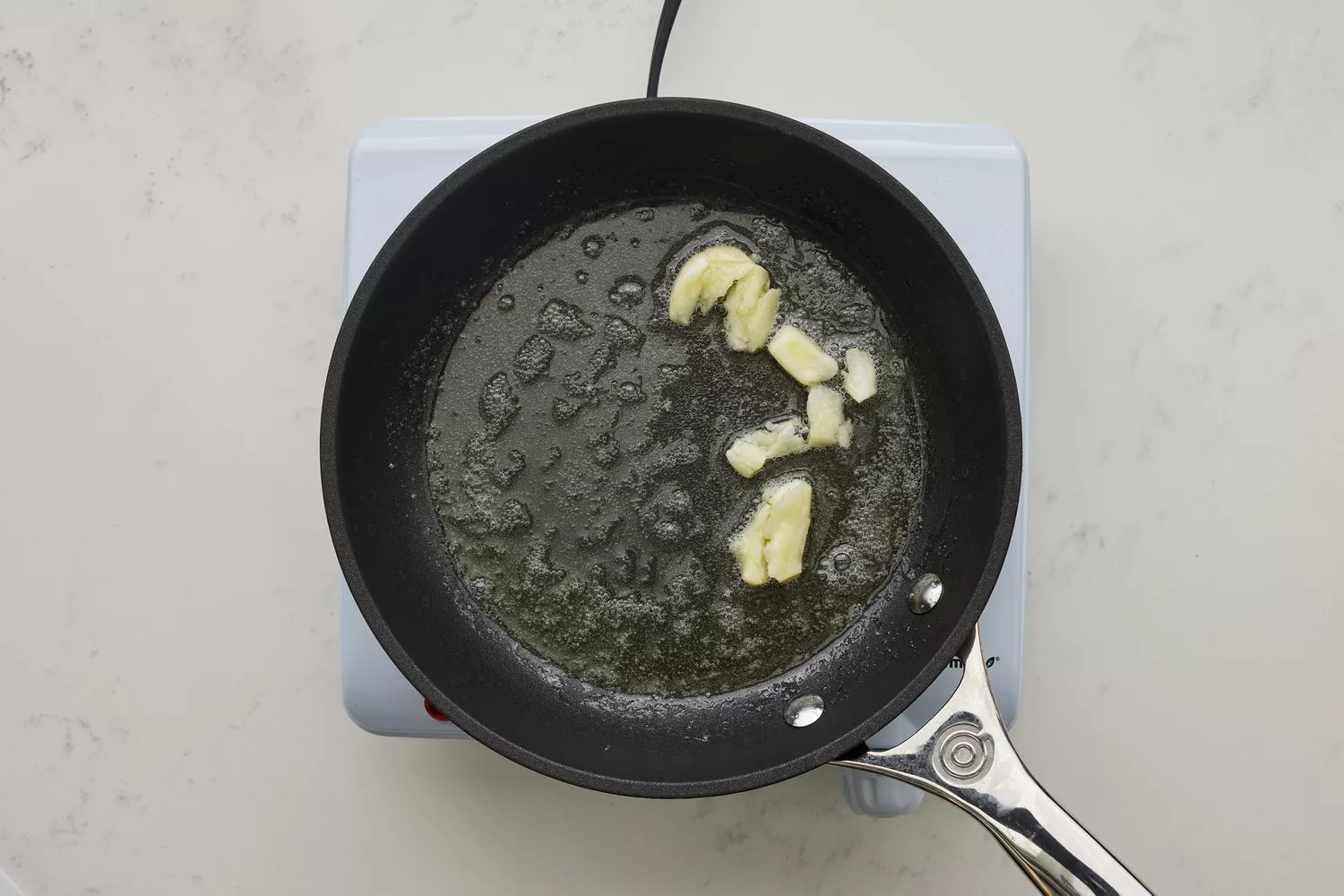 Une poêle avec du beurre fondu, de l'ail écrasé et du jus de citron