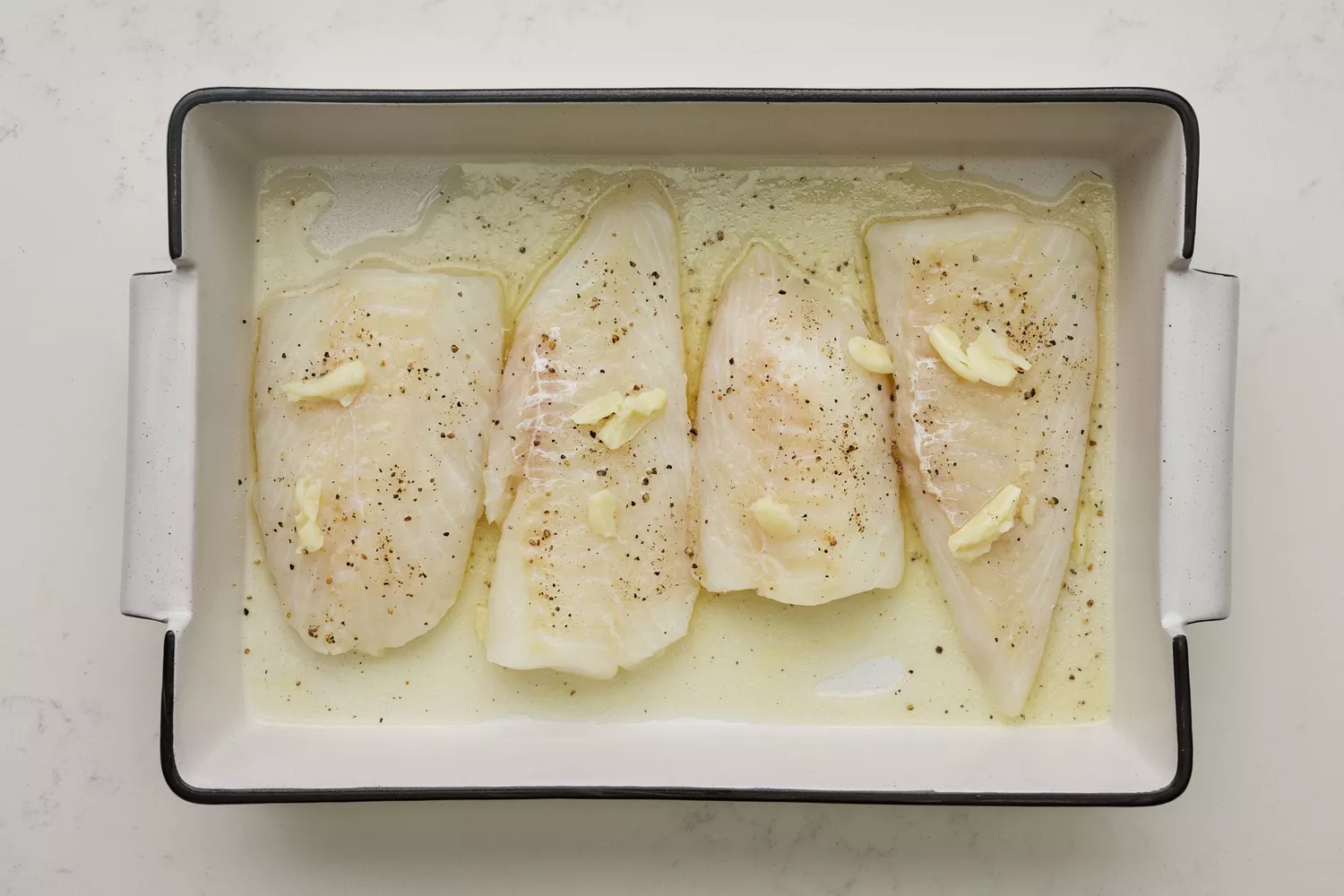 Un plat avec quatre filets de morue, nappés de sauce ail-beurre-citron