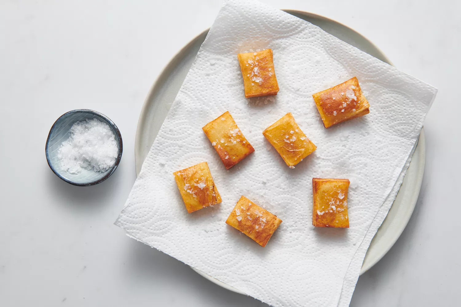 Une assiette garnie de pommes de terre en mille-feuille saupoudrées de sel