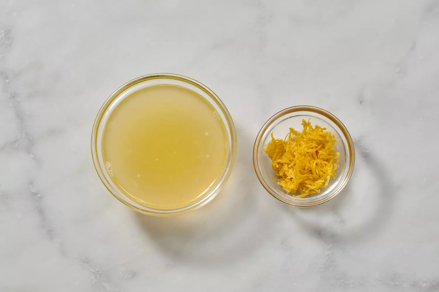 Un petit bol de jus de citron frais et un petit bol de zeste de citron