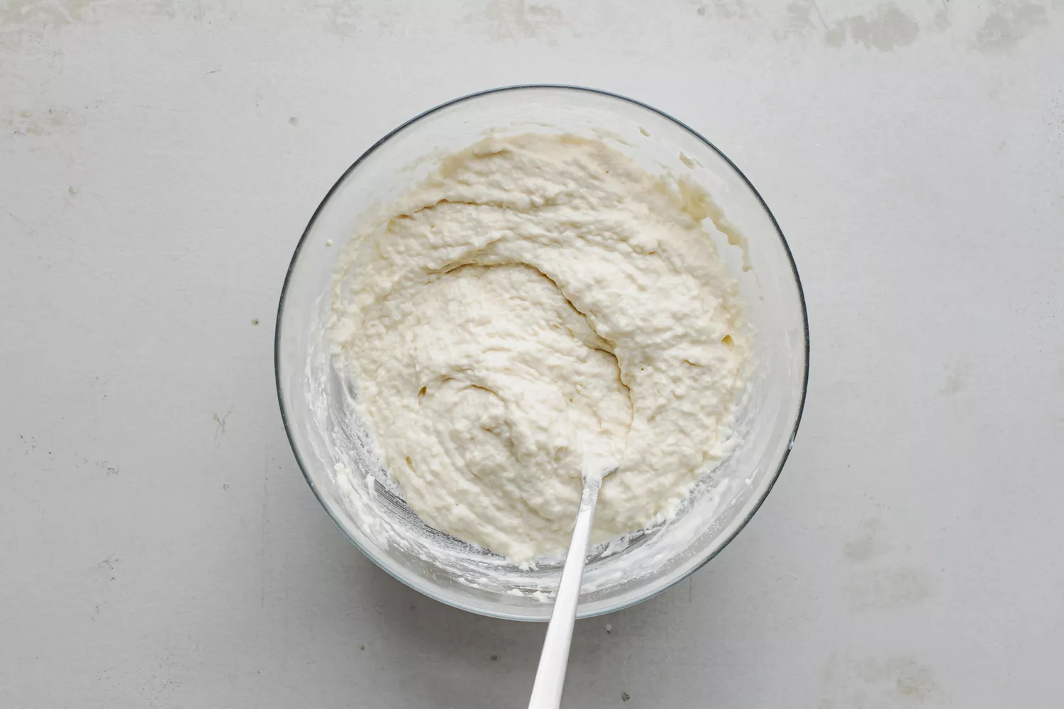 Du lait ajouté au mélange de farine et mélangé avec une cuillère à une consistance épaisse