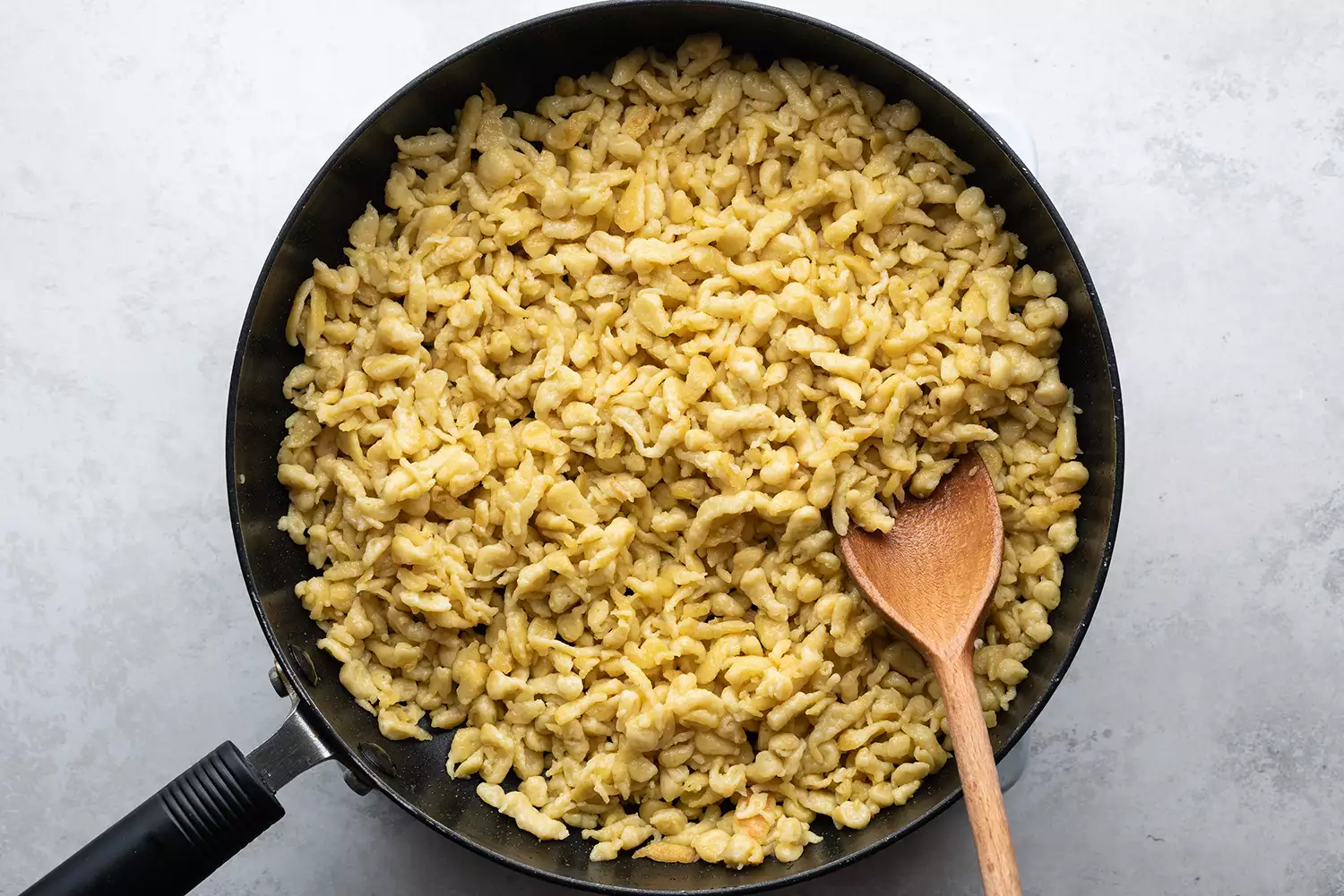 Spaetzle allemand dans une poêle avec une cuillère en bois 