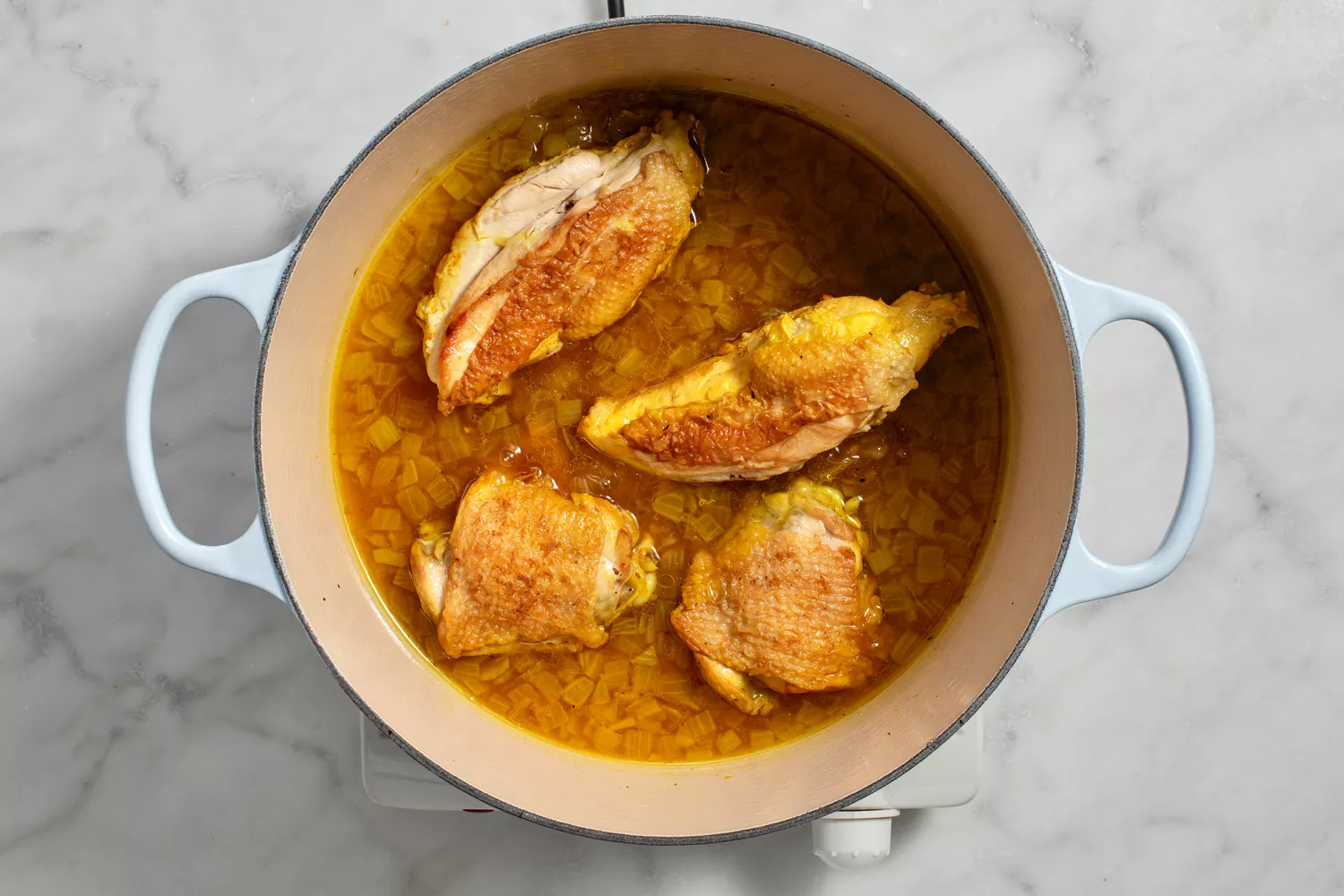 water and chicken pieces added to pot with onions