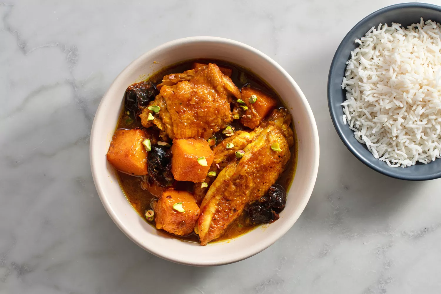 bowl of finished stew garnished with pistachios, bowl of rice on the side