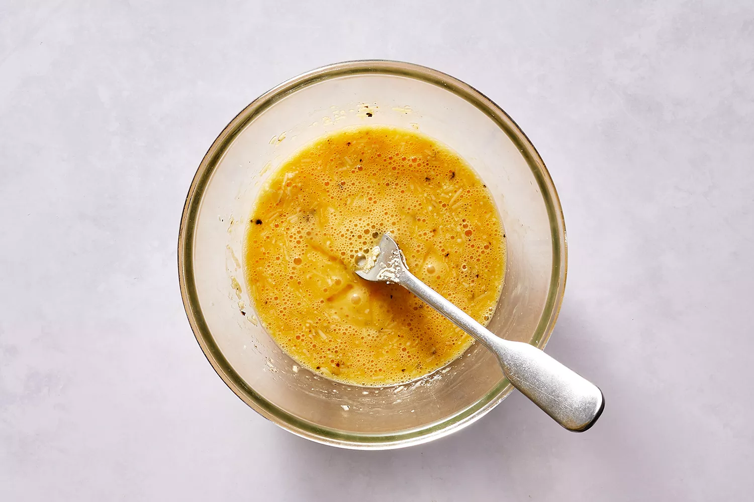 Œuf, fromage et poivre noir mélangés ensemble avec une fourchette