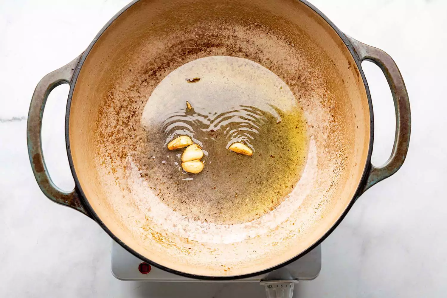 Ail dans une casserole avec de l'huile, sur une cuisinière