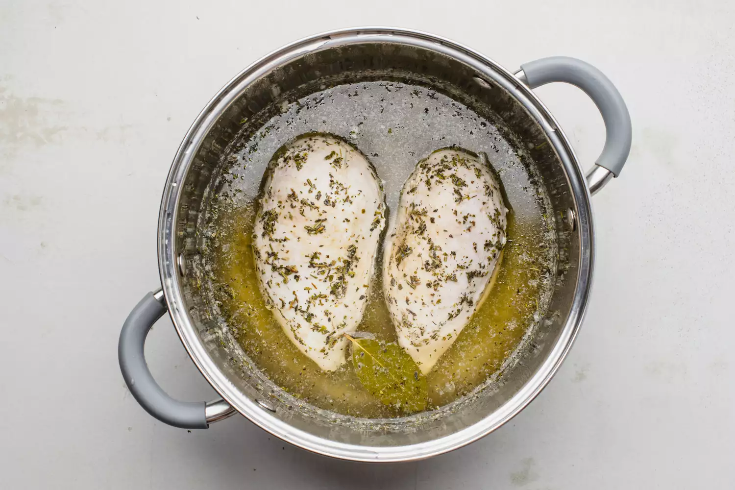 Poitrines de poulet pochées dans le bouillon reposant dans la casserole