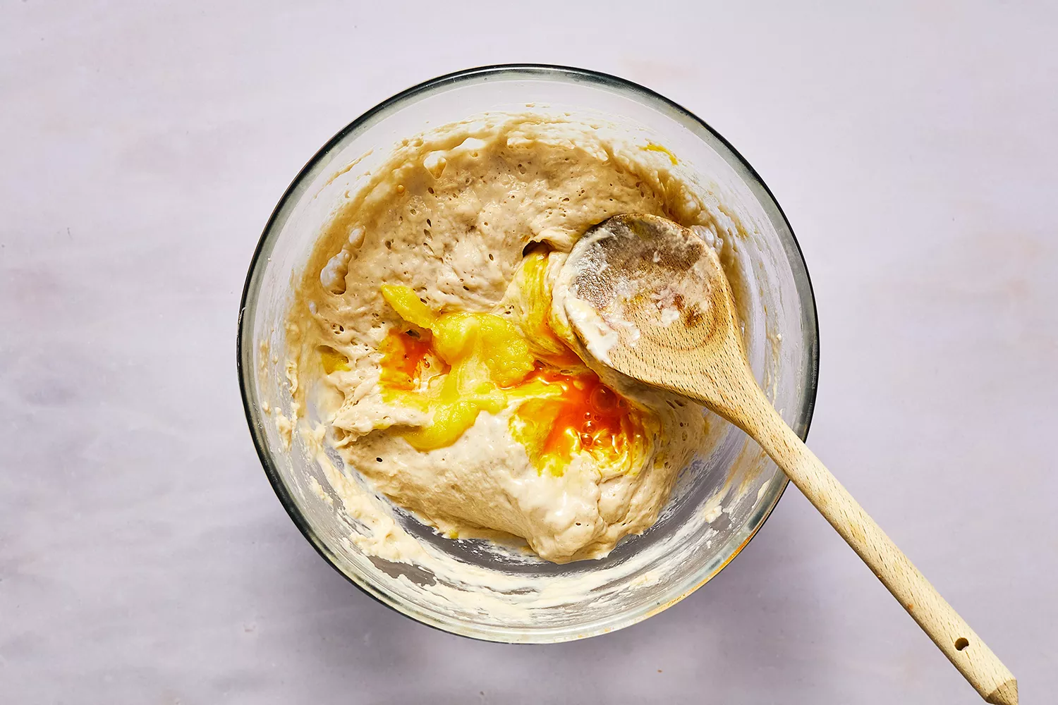 Pâte à blinis dans un bol avec œuf et une cuillère en bois