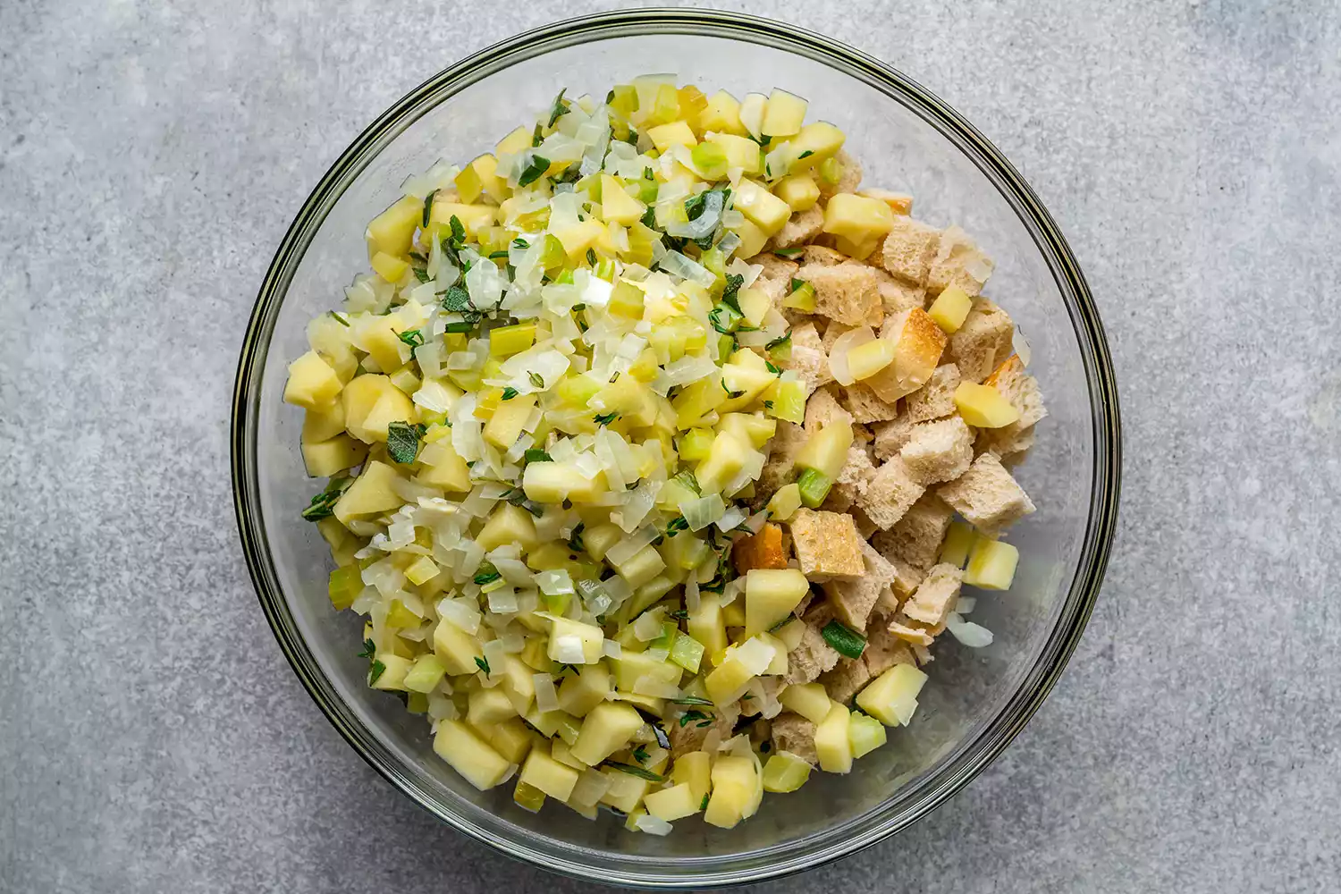 cooked onions, celery, and apples in a bowl with cubed bread