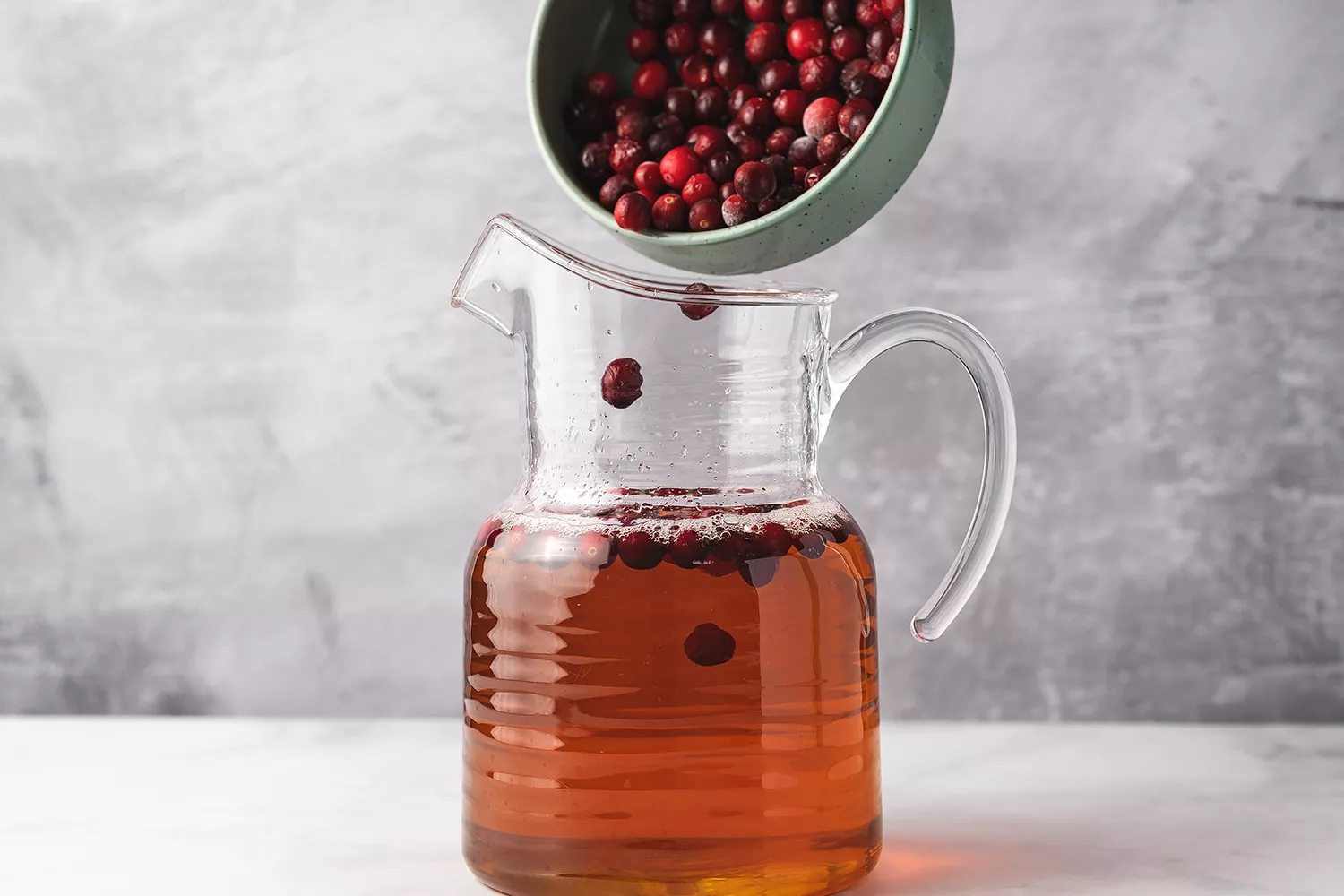 Cranberries ajoutées au cidre dans un pichet en verre